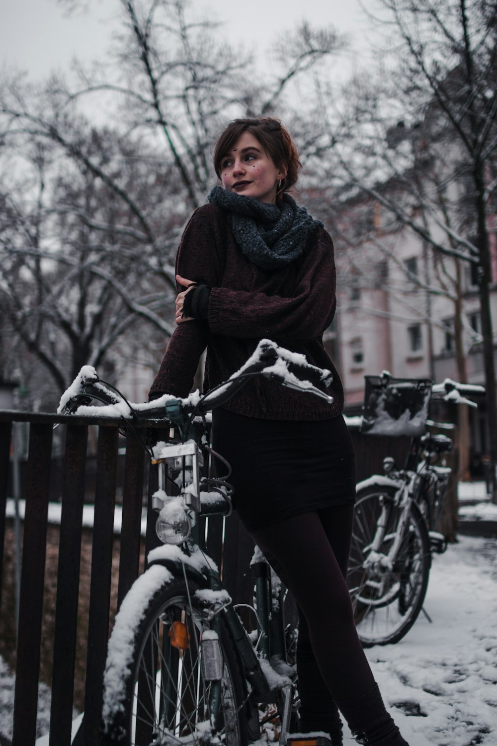woman leaning on brown rails and bike near trees
