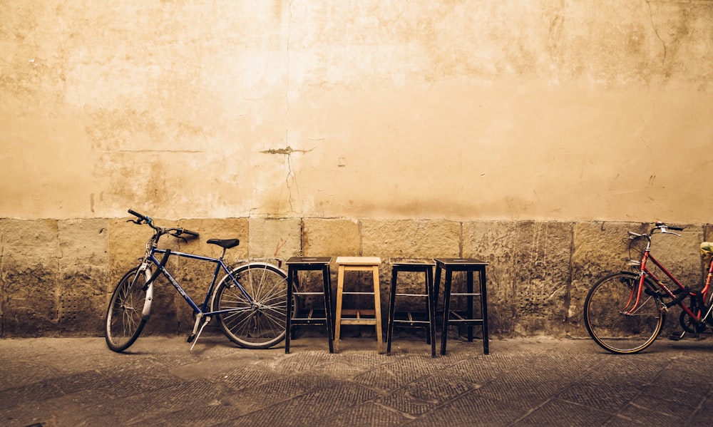 four bar stools near two bikes leaning on wall