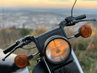 Close-up of a motorcycle with bright LED auxiliary lights glowing at dusk.