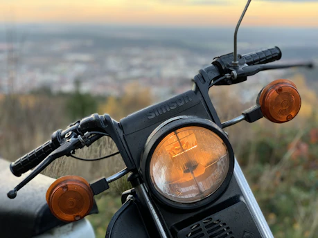 Close-up of a motorcycle with bright LED auxiliary lights glowing at dusk.