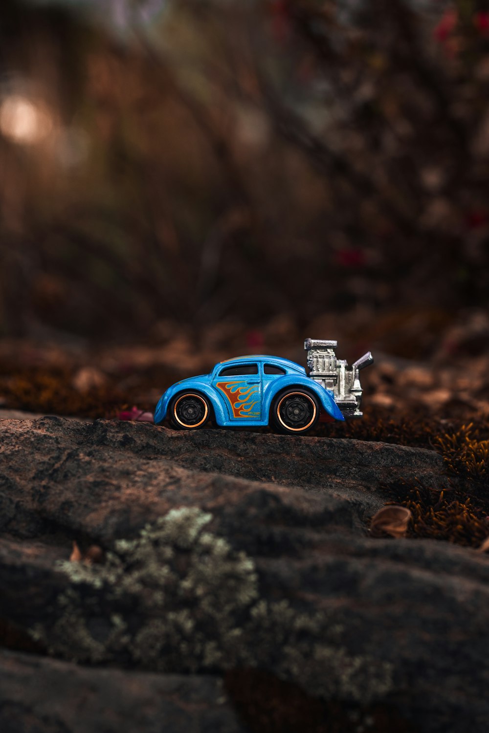 blue die-cast metal hot rod toy on grey rock