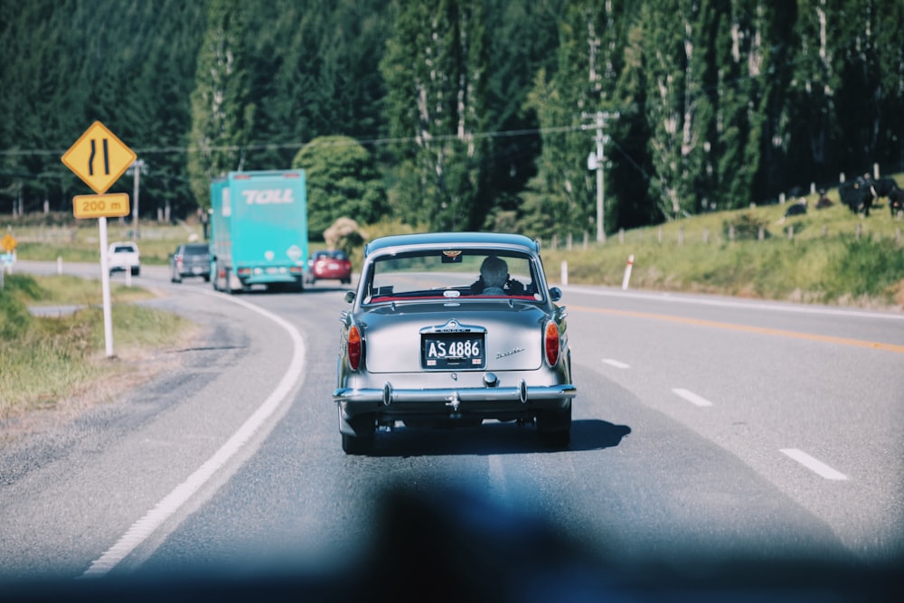 gray car on road next to green truck