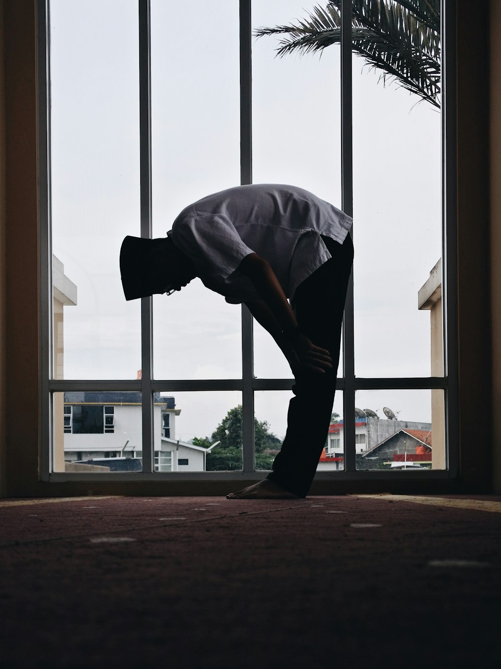 man holding his knees near window