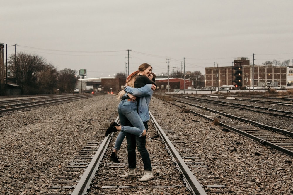 man lifting woman on railway during daytime