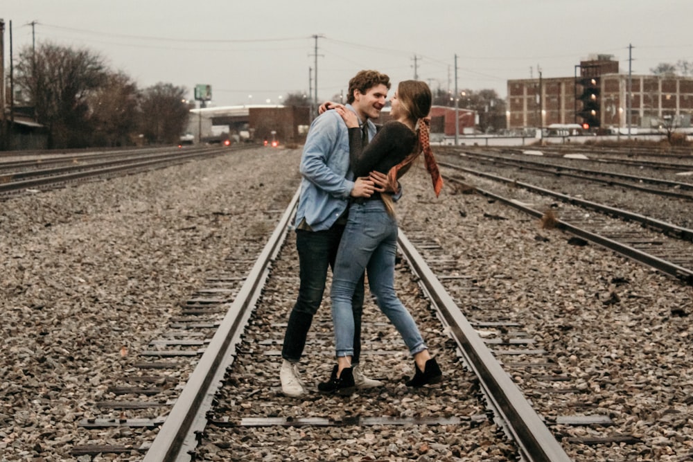 woman and man standing on train track during daytime