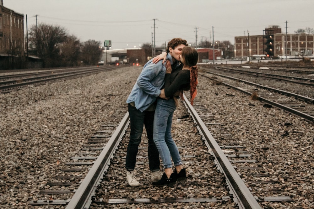 couple kissing in the middle of railroad