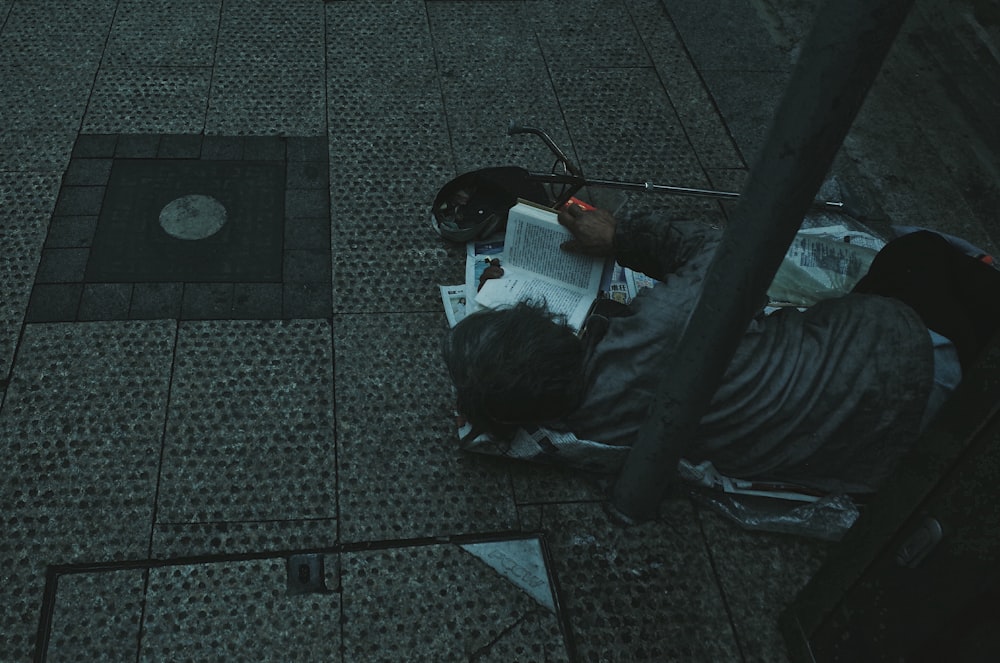 uomo sdraiato su carta grigia mentre legge la bibbia