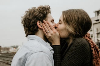 A playful couple sharing a spontaneous kiss in a cozy urban setting.