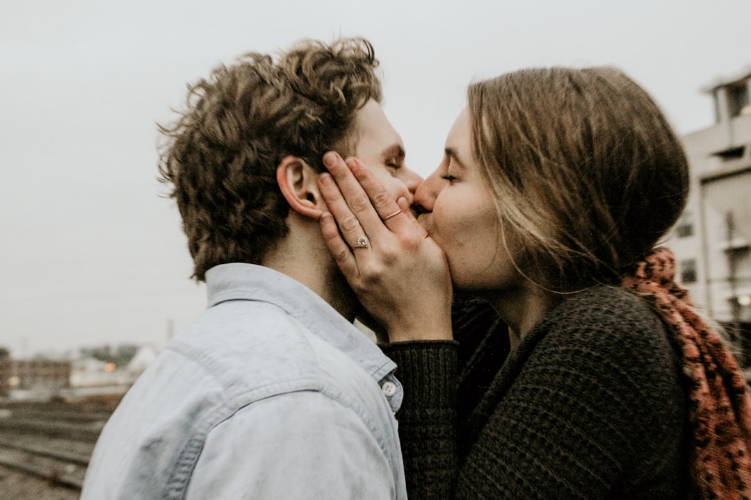 couple kissing under gray clouds,