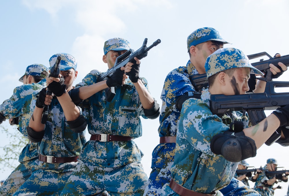 five men pointing rifles during day