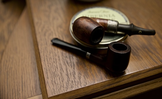 two black and brown wooden smoking pipes on table
