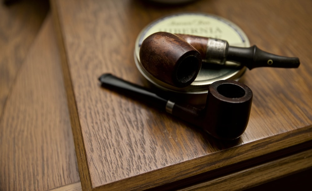 two black and brown wooden smoking pipes on table