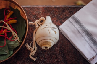 A serene setting showing a bowl of white flowers and a set of cowrie shells used for divination.