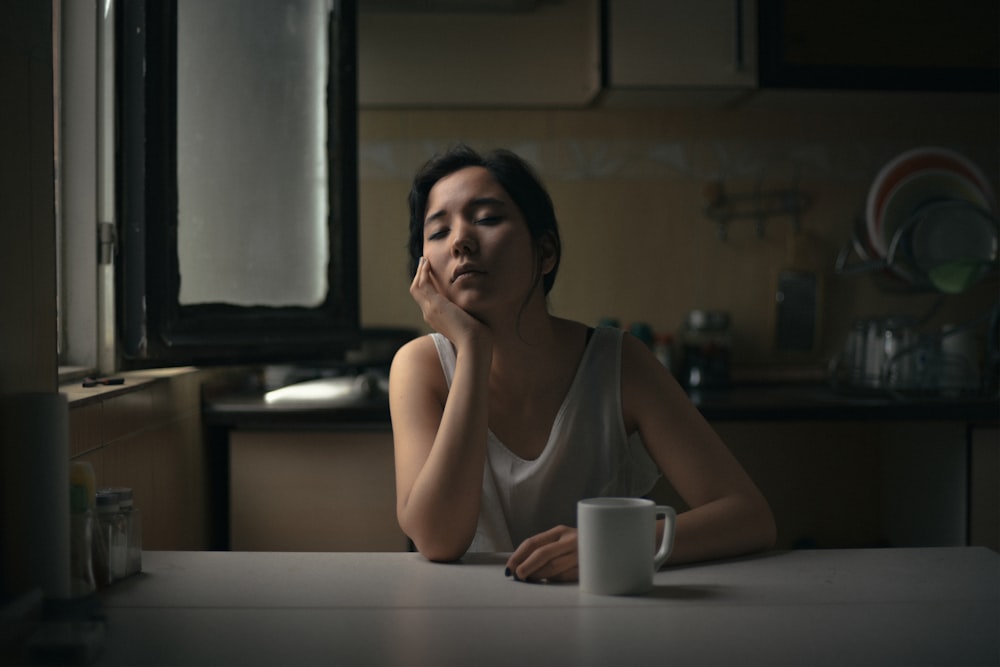 woman in white tank top in front of white wooden table