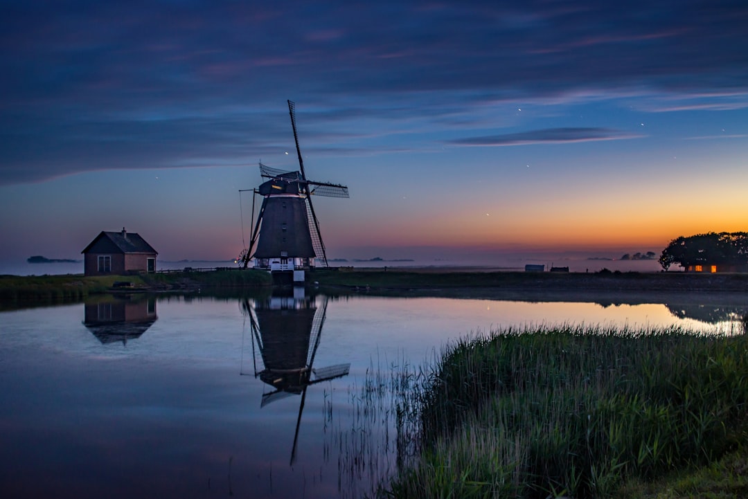 windmill near lake during golden hour