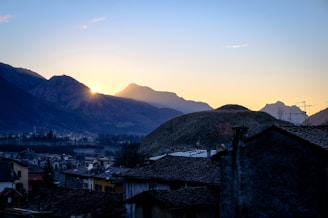 Sunrise over rugged mountain peaks with a small wooden lodge in the foreground.