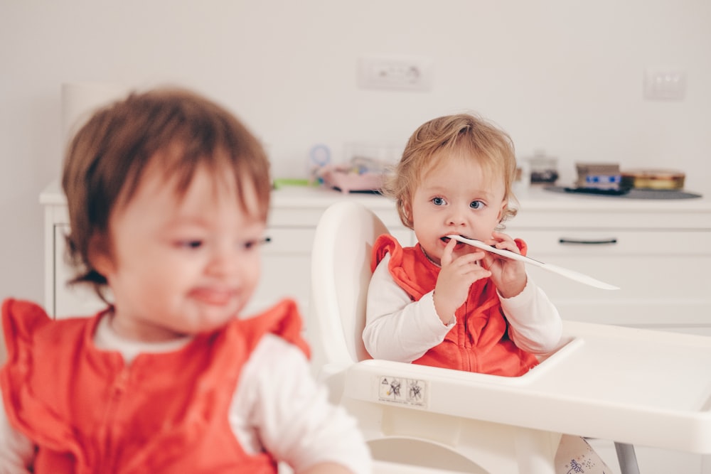 selective focus photography of baby on highchair biting paper