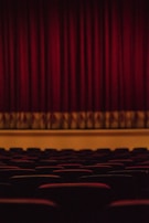 An intimate theater scene with actors performing under warm stage lighting.