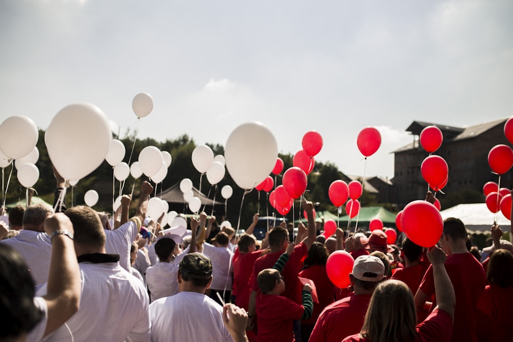 people holding red and white balloons