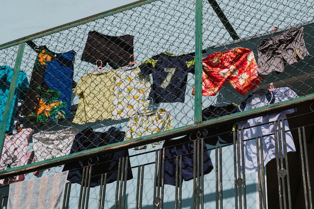 assorted-color clothes hung on fence