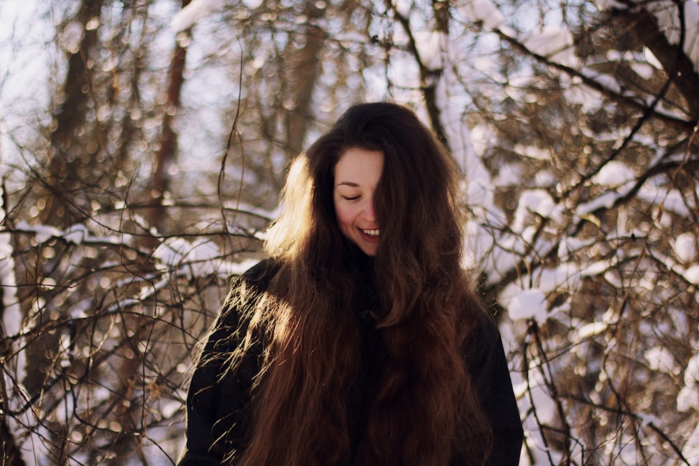 woman in black jacket standing by bare trees during daytime