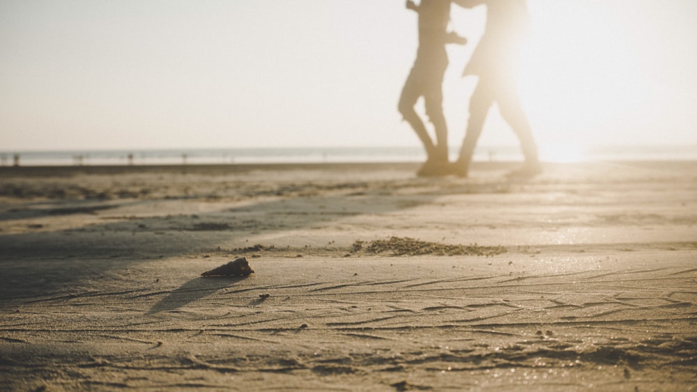 due persone che camminano sulla sabbia durante il giorno