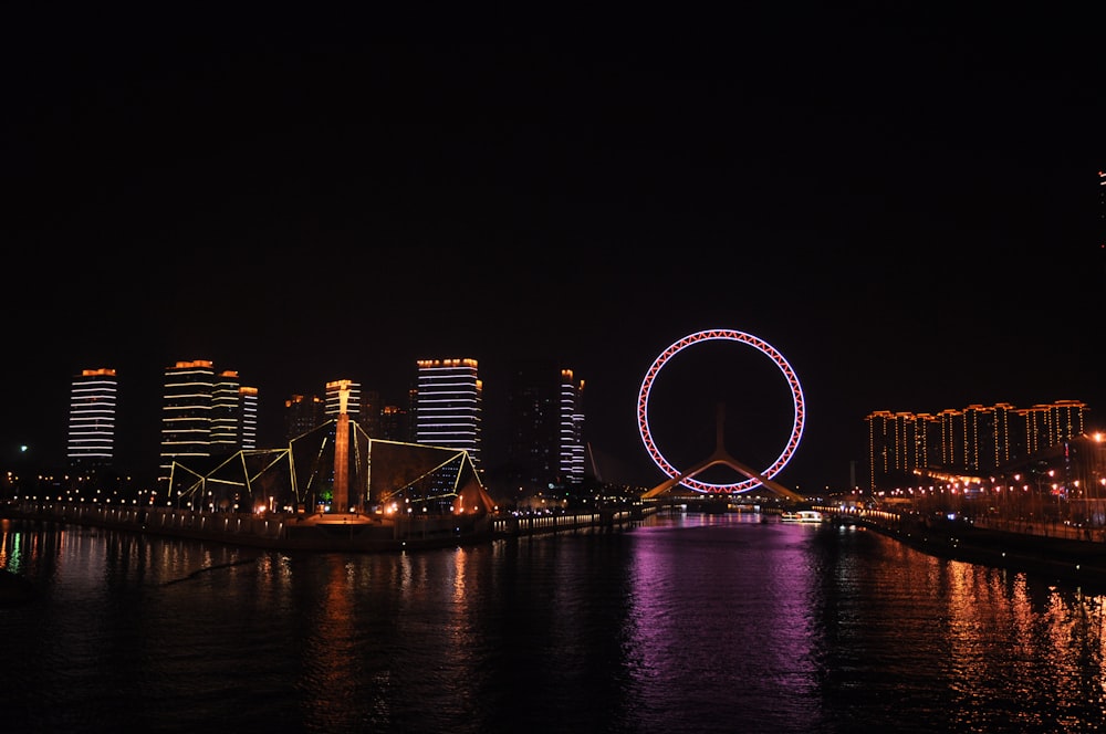 Cidade e roda gigante com luzes durante a noite