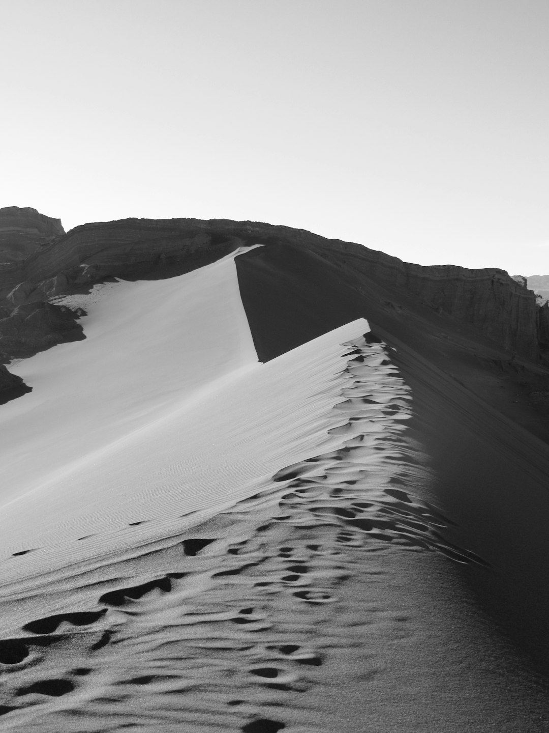 grayscale photography of footprints on desert mountain