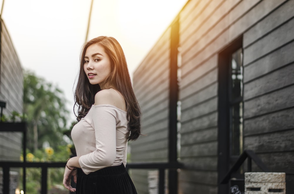 woman wearing grey off-shoulder long-sleeved shirt standing near handrail