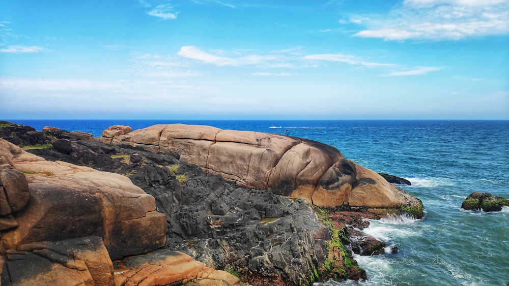 pedra marrom perto do corpo de água durante o dia