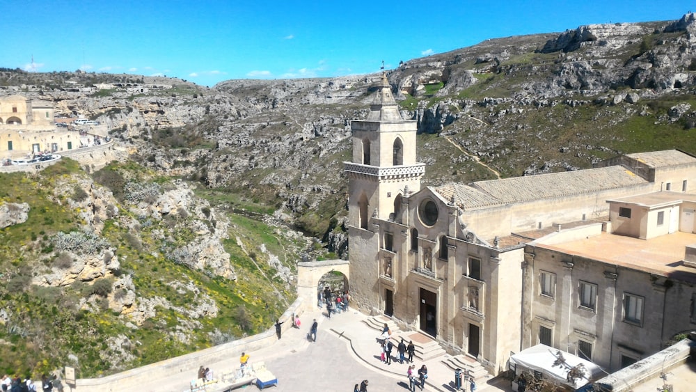 people walking in front of cathedral near the mountains