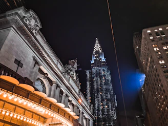 An urban nightscape featuring art deco architecture illuminated by warm streetlights.