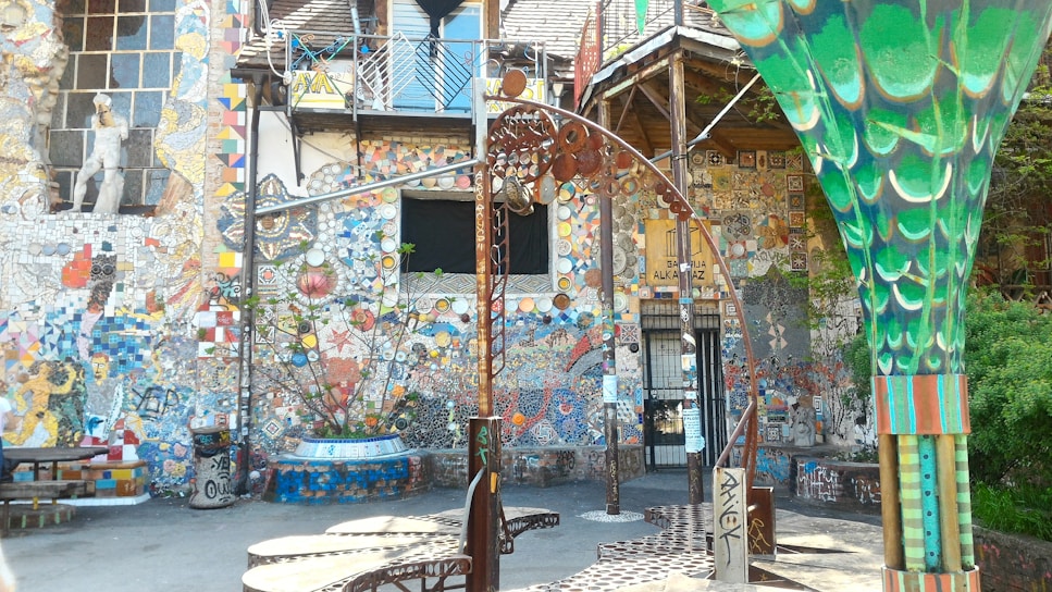 A bright, welcoming community center courtyard filled with families and children playing around modern art installations.