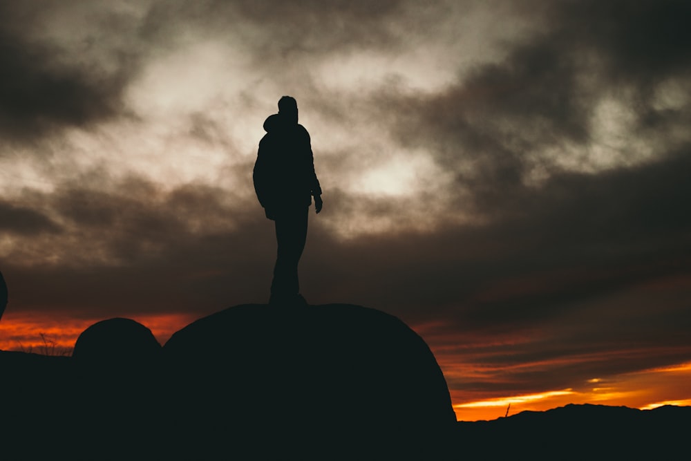 man standing on rock during golden hour