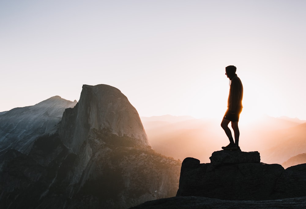 silhouette photo of man standing on hill