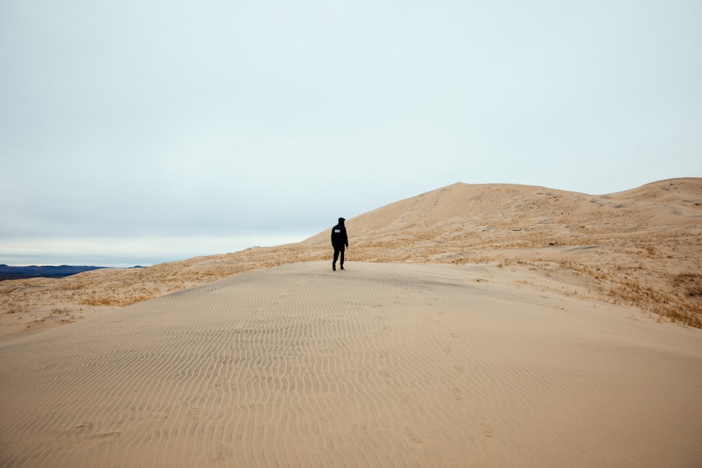 pessoa andando no campo de areia durante o dia