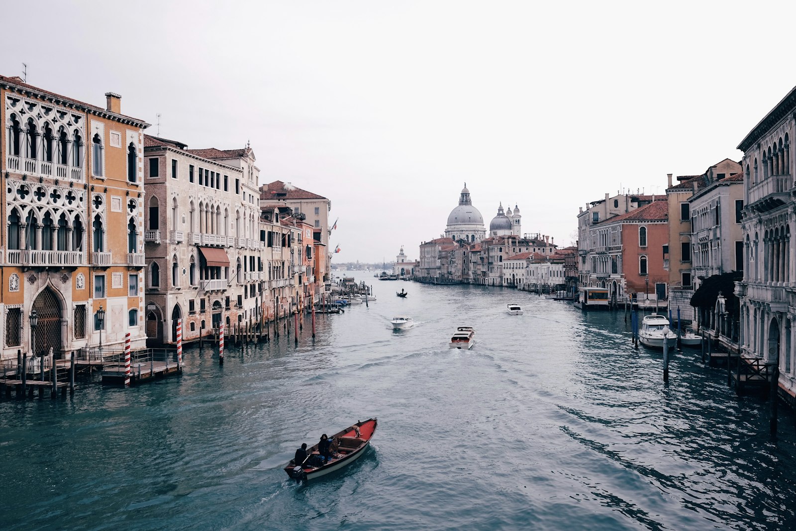 Boats on Venice's Grand Canal lined with palazzi, with the dome of Santa Maria della Salute in the distance
