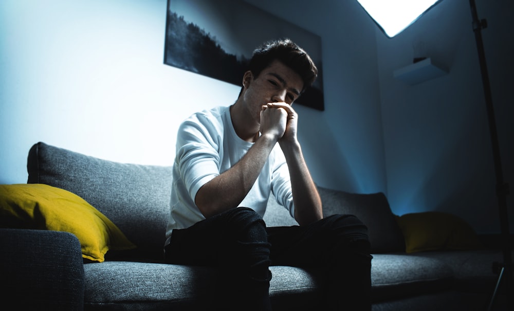 boy in white shirt and black pants sitting on gray fabric sofa