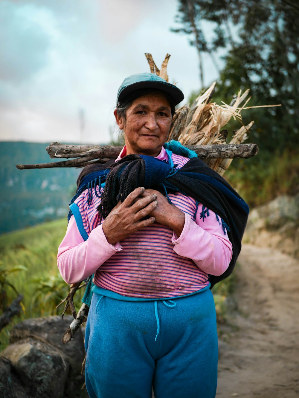 woman standing while carrying firewoods on her back\