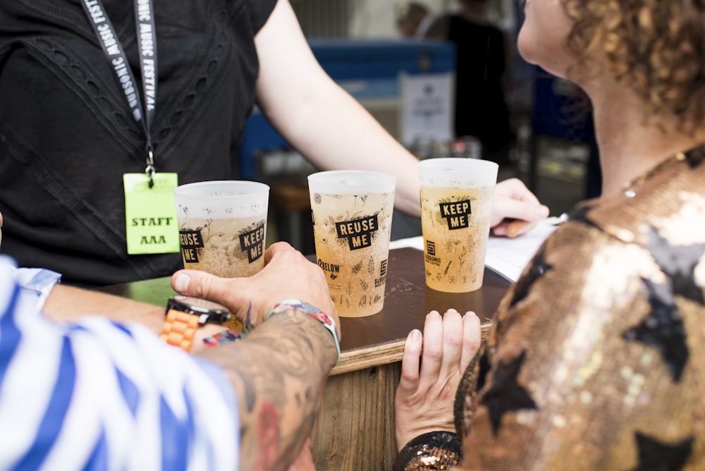 drei gefüllte Reuse Me-Becher auf braunem Tisch