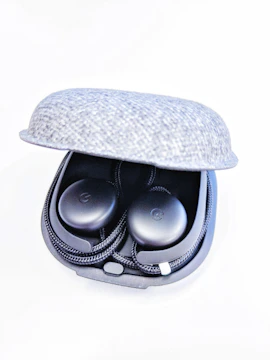 A lineup of sleek wireless earbuds resting on a textured dark gray fabric.