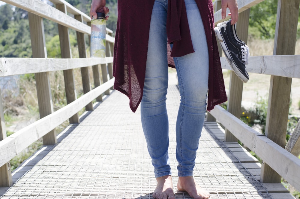 person holding pair of black low-top sneakers