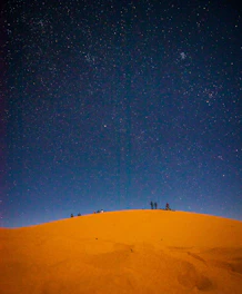 Group of travelers sharing a sunset moment in the Sahara Desert camp under starry skies.