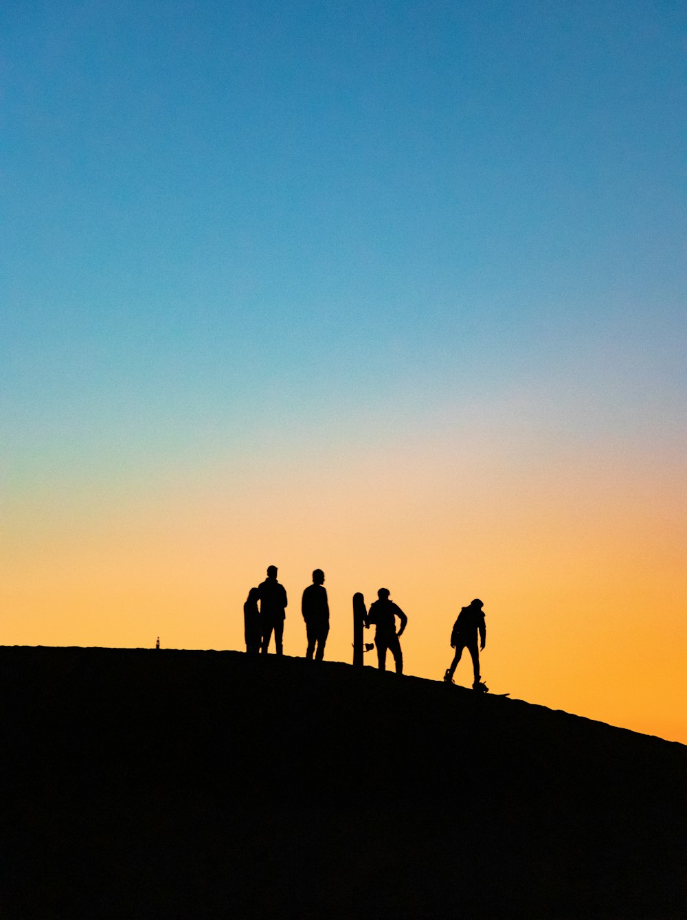 silhouette photography of four people holding snowboards