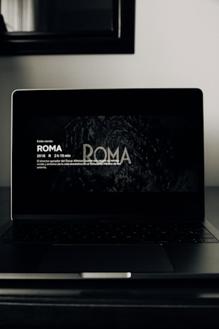 Dark-themed cinematic interface showing featured movies on a sleek laptop screen.