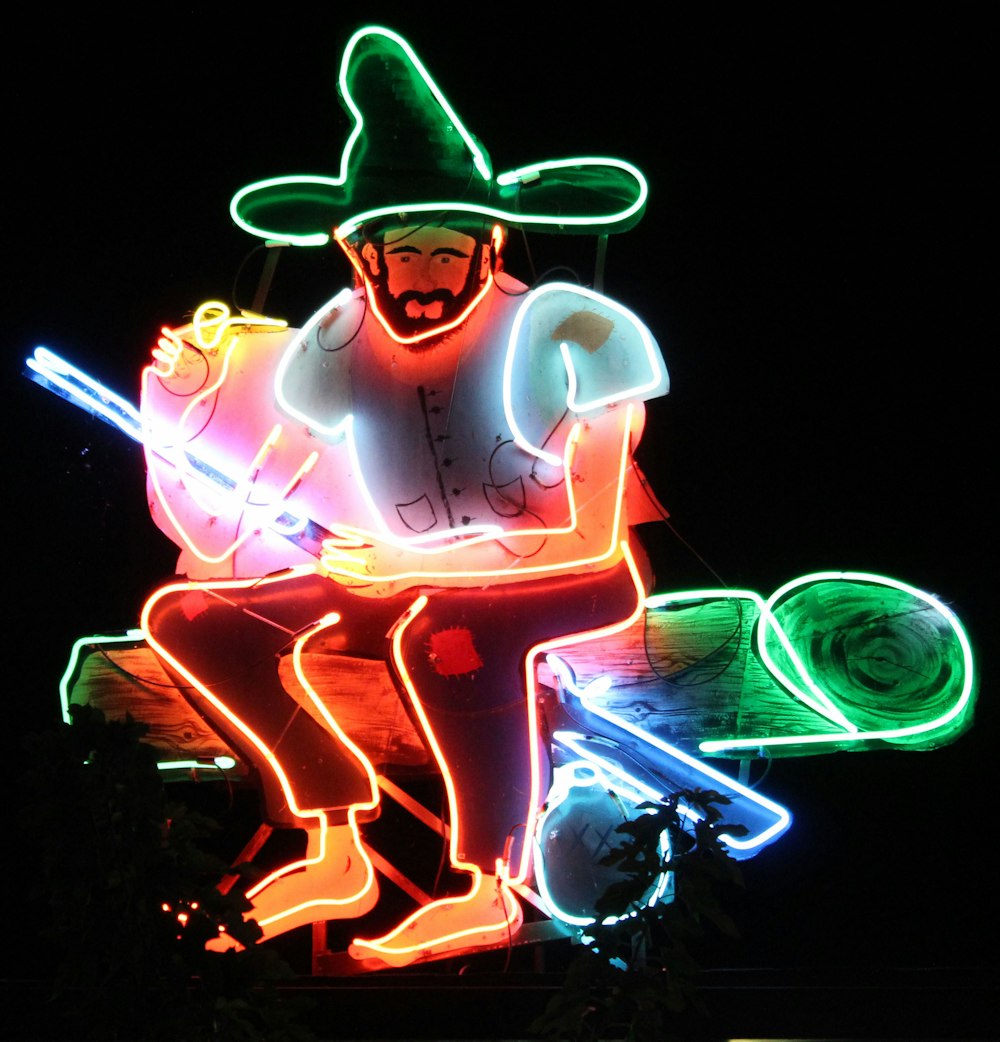 man sitting on log lighted artwork