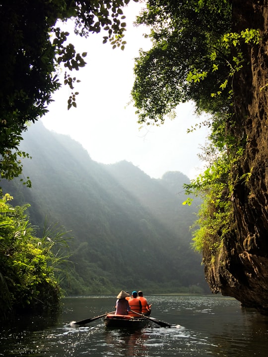 group of people on boat paddling during daytime in Tràng An Vietnam