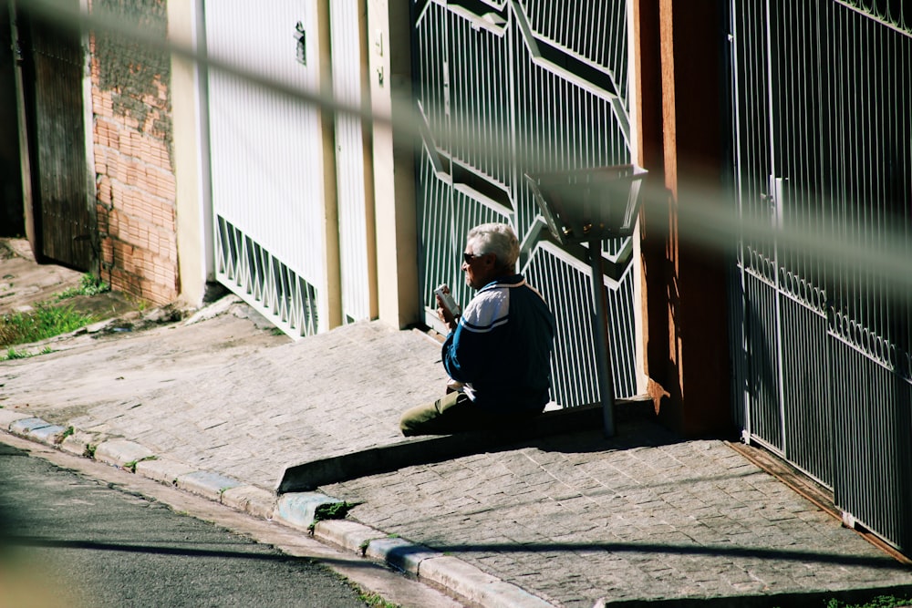 man sitting on concrete ground beside gate