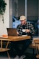 man sitting while having coffee and using laptop