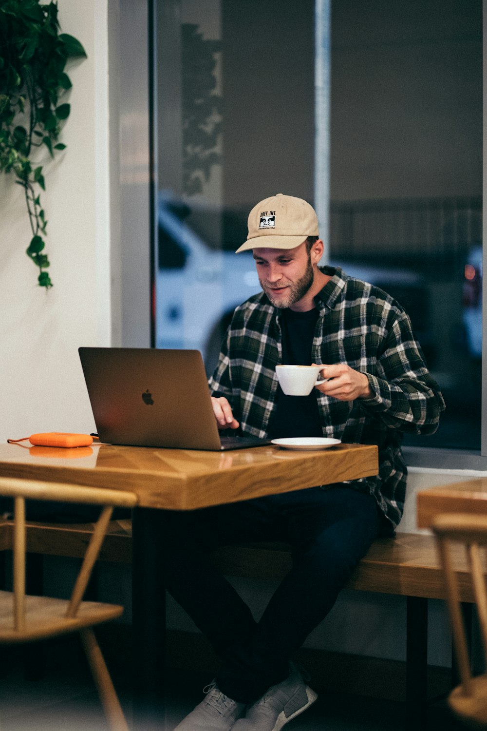 Hombre sentado mientras toma café y usa una computadora portátil